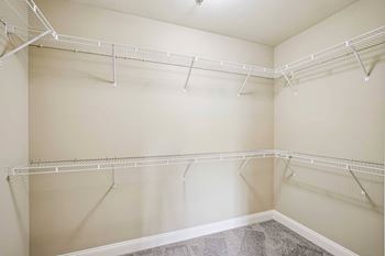 Empty white closet with shelves and hangers.